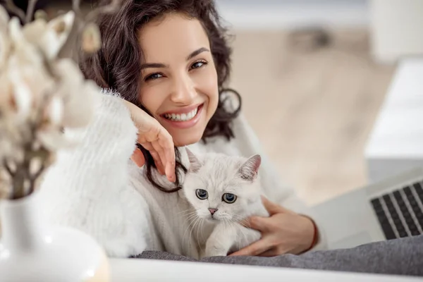 Мила молода жінка тримає білого кота і гарно посміхається — стокове фото
