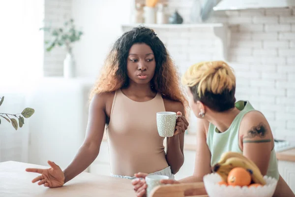 Razonamiento de la mujer afroamericana con café y novia escucha —  Fotos de Stock