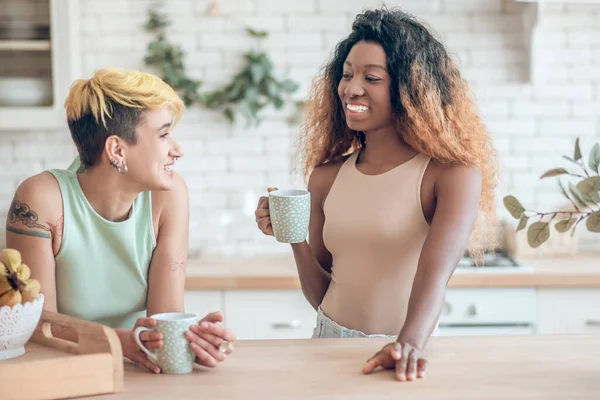 Dos novias alegres hablando en la cocina con café —  Fotos de Stock