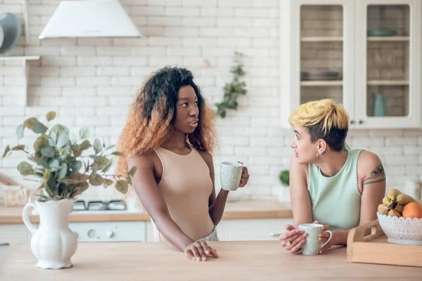 Dos amigas charlando tomando café en la cocina —  Fotos de Stock