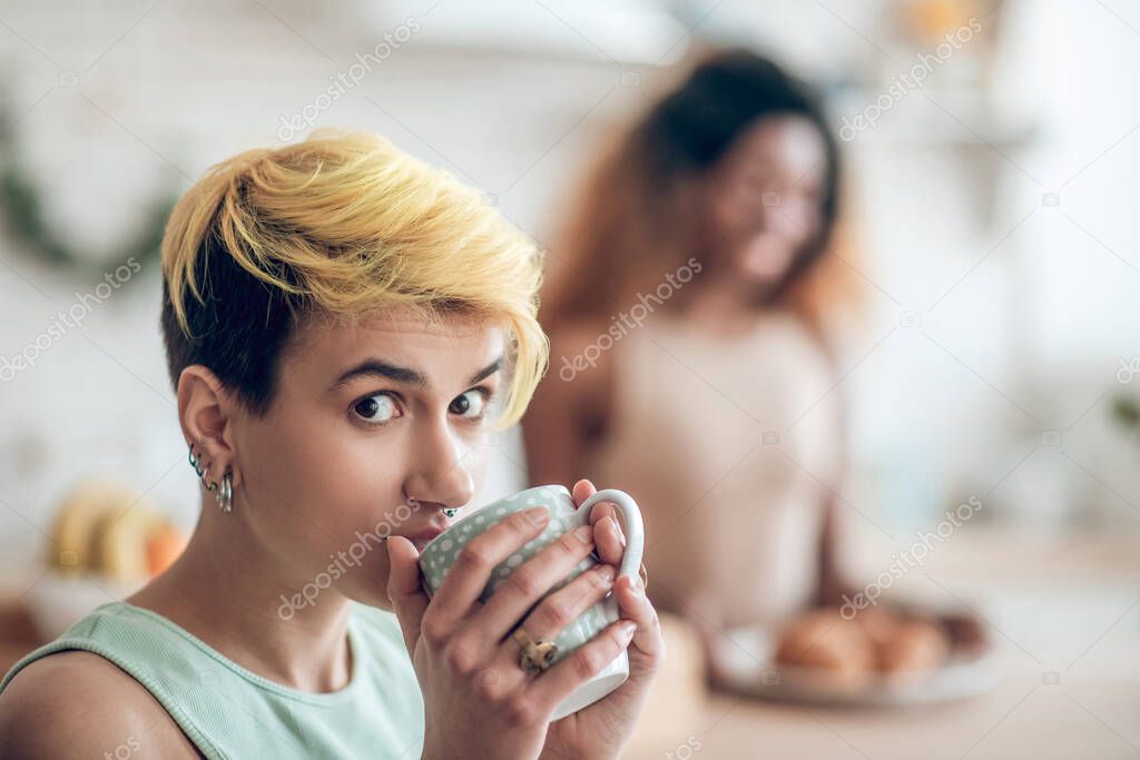 Face of young woman looking with interest with cup