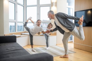 Babaları ve çocukları evde yoga yapıyor ve olaya dahil olmuşlar.