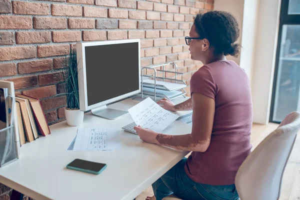 Eine Frau mit Brille, die am Computer arbeitet und beschäftigt aussieht — Stockfoto