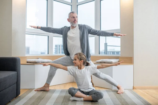 Papá y sus hijos haciendo yoga juntos en casa y buscando involucrados — Foto de Stock