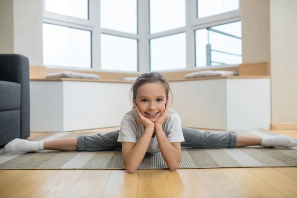 Roztomilé dívka sedí na podlaze a protahování — Stock fotografie