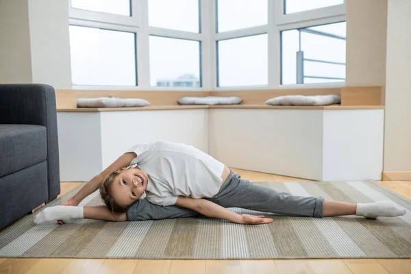 Ragazza carina seduta sul pavimento e stretching — Foto Stock