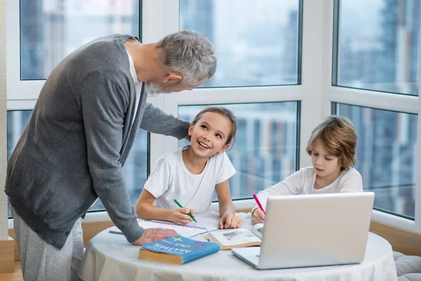 Père aider les enfants avec des leçons et leur expliquer quelque chose — Photo