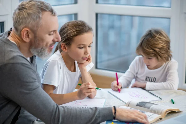 Père aider les enfants avec des leçons et leur expliquer quelque chose — Photo