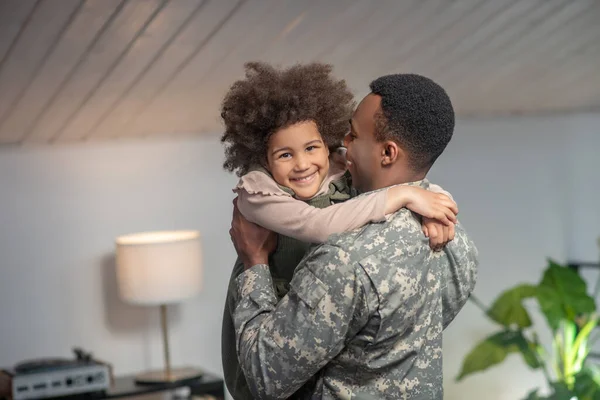 Gelukkig klein meisje in armen van militair man — Stockfoto