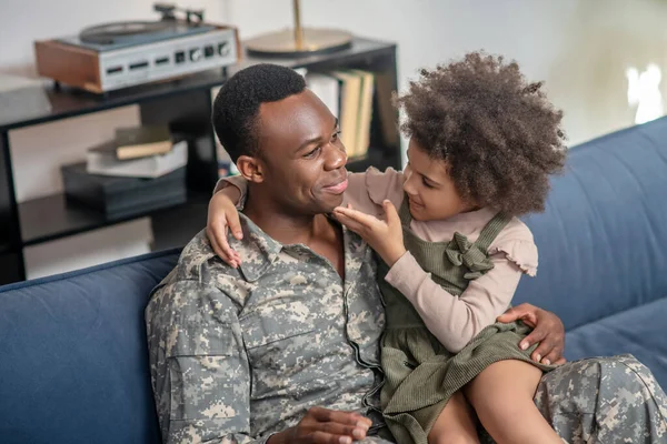 Κοριτσάκι που κάθεται στην αγκαλιά του στρατιωτικού πατέρα — Φωτογραφία Αρχείου