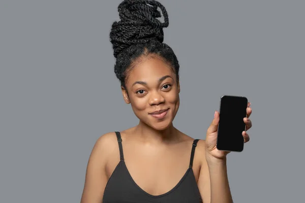 Kvinna med hår bulle i svarta kläder med en smartphone — Stockfoto