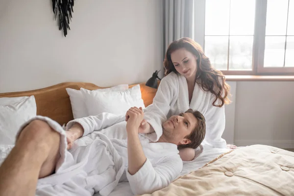 Una pareja de albornoces blancos acostados en la cama y enamorados —  Fotos de Stock