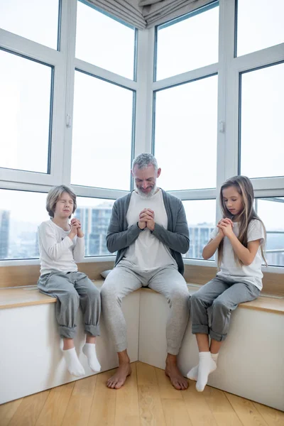 Gray-haired man en zijn kinderen zitten vreedzaam met namaste — Stockfoto