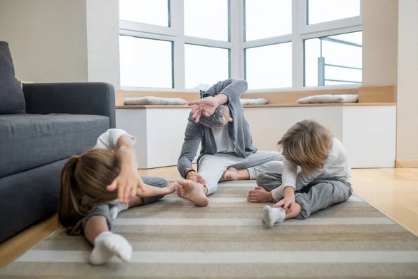 Padre addestrare i suoi figli a casa facendoli allungare correttamente — Foto Stock