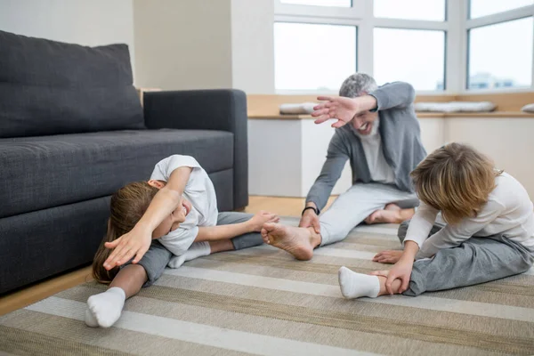 Vader die zijn kinderen thuis traint zodat ze goed strekken. — Stockfoto