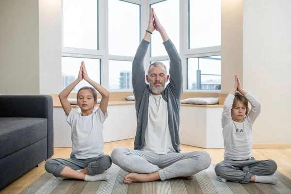 Padre y sus hijos haciendo yoga juntos en casa y buscando la paz — Foto de Stock