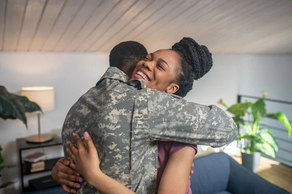 Szczęśliwa kobieta z zamkniętymi oczami przytulająca wojskowego mężczyznę — Zdjęcie stockowe