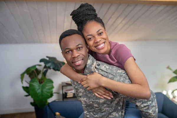 Happy military man holding wife on his back