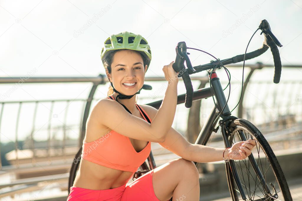 Female cyclist in protective helmet llooking happy and contented