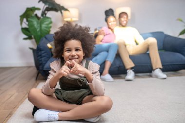 Kalbini gösteren kız parmakları ve ailesi arkada