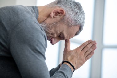 Gri saçlı bir adam gözleri kapalı oturuyor ve ödeyenlere...