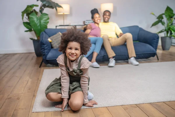 Dcera na podlaze a objala rodiče na gauči — Stock fotografie
