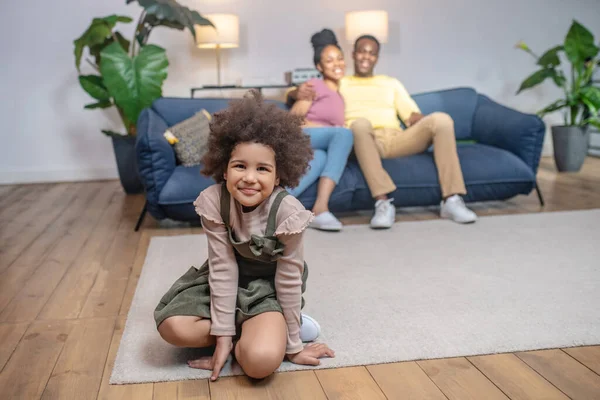 Dochter op de vloer en knuffelde ouders op de bank — Stockfoto