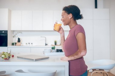 Koyu tenli bir kadın portakal suyu içiyor.