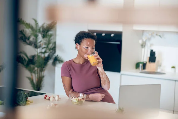 Una mujer de piel oscura bebiendo un jugo de naranja — Foto de Stock