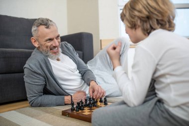Baba oğul satranç oynuyor ve ilgili görünüyor.