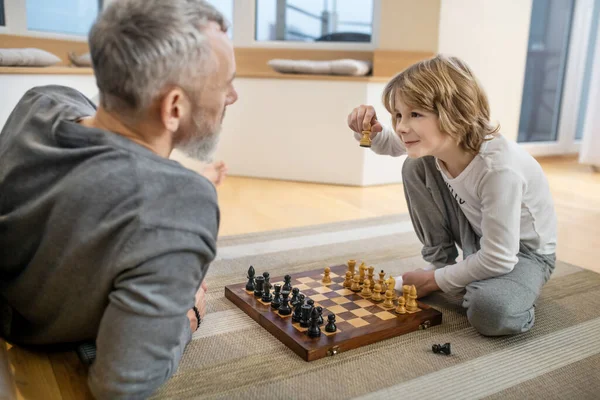 Father and son playing chess and looking involved