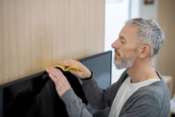 Un hombre barbudo limpiando la casa y buscando involucrado — Foto de Stock