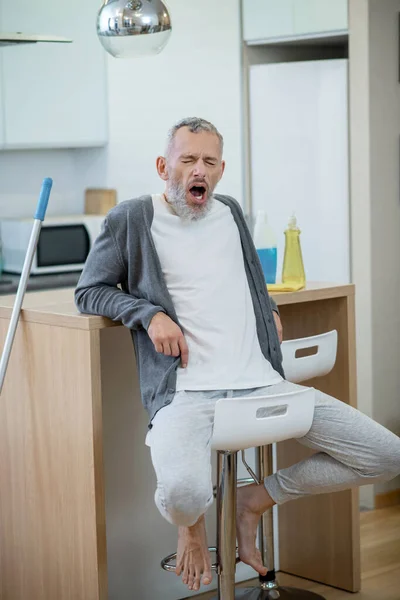 Hombre en ropa de casa descansando después de limpiar la casa y sintiéndose aburrido — Foto de Stock