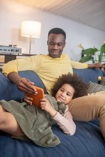 Dark-skinned dad with little daughter looking at tablet — 스톡 사진