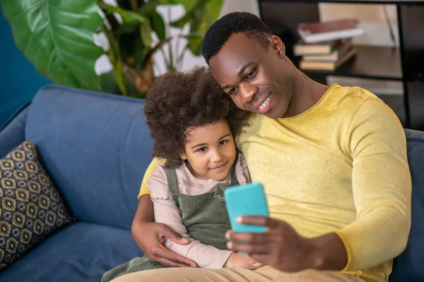 Niña con papá abrazándose mirando en el teléfono inteligente — Foto de Stock
