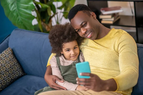 Klein meisje met papa knuffelen op zoek naar smartphone — Stockfoto