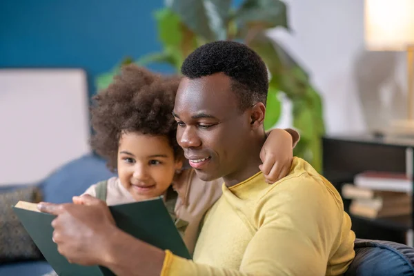 Dochter knuffelen door nek vader lezen boek — Stockfoto