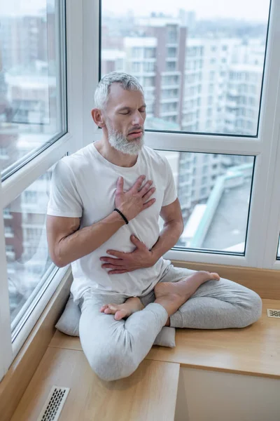 Ein reifer Yogi macht Pranayama und sieht meditativ aus — Stockfoto