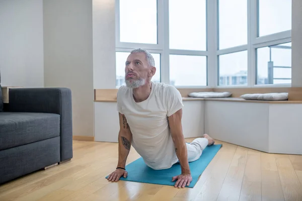 Un yogui maduro haciendo ejercicio en casa y luciendo flexible — Foto de Stock