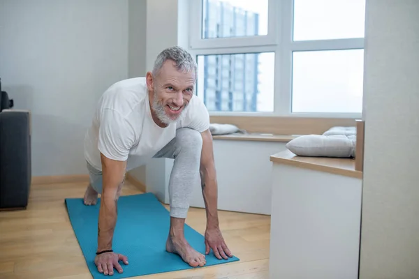 Yetişkin bir adam evde yoga yapıyor ve konsantre görünüyor. — Stok fotoğraf