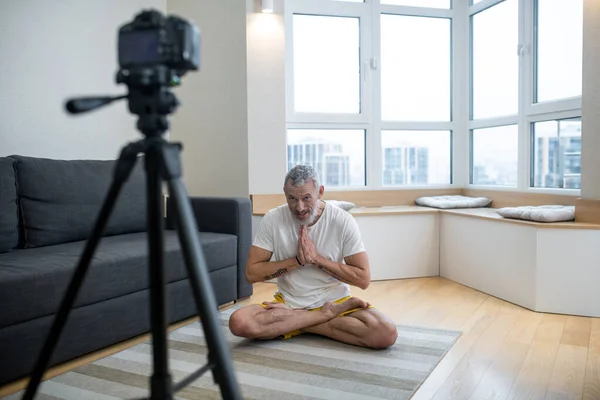 Un hombre maduro en camiseta blanca practicando yoga en línea — Foto de Stock