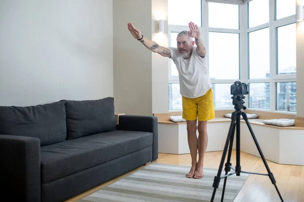 Un hombre maduro en camiseta blanca practicando yoga en línea — Foto de Stock