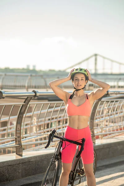 Joven ciclista en ropa deportiva brillante de pie en el puente — Foto de Stock