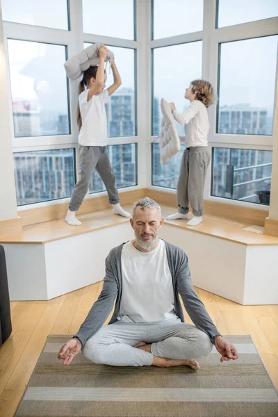 Hermanos teniendo una pelea de almohadas mientras su padre hace yoga — Foto de Stock