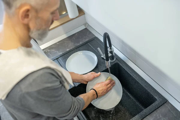 Närbild av en man som tvättar tallrikarna i köket — Stockfoto