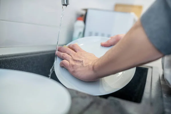 Um homem de cabelos grisalhos a limpar o frigorífico na cozinha — Fotografia de Stock