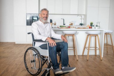 Gri saçlı, olgun, engelli bir adam.