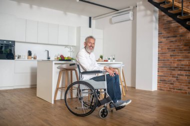 Gri saçlı, olgun, engelli bir adam.