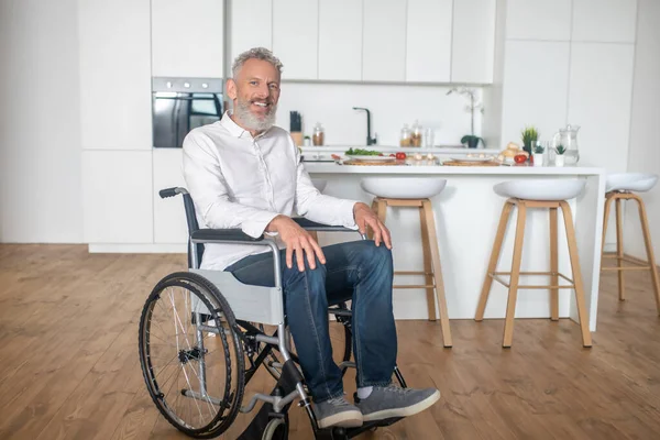 Gri saçlı, olgun, engelli bir adam.