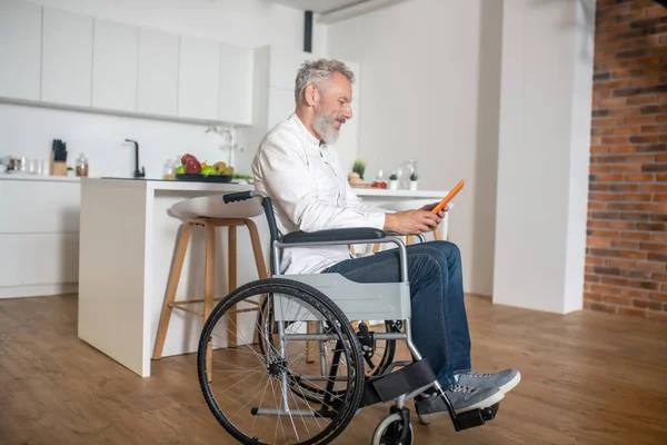 Gray-haired handicapped man with a tablet in hands — Stock Photo, Image